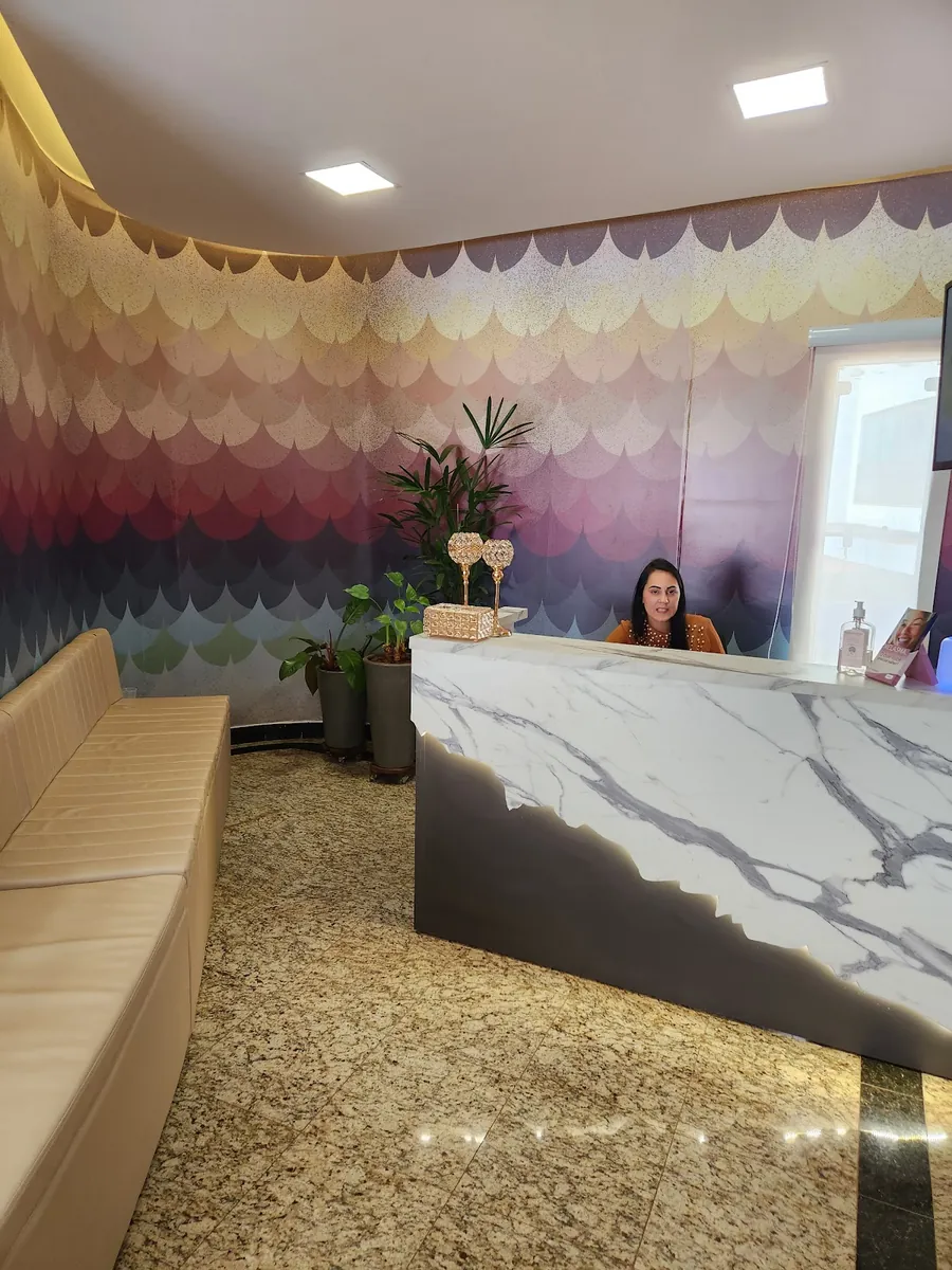 Recepção da clínica com balcão de mármore e parede decorada